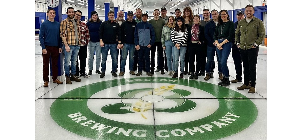 Photo of the Breton Brewing team on the ice of a curling rink with the Breton Brewing logo painted on the ice