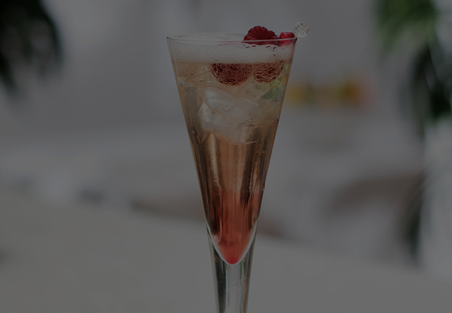 A tall champagne glass filled with a sparkling rose cocktail. 