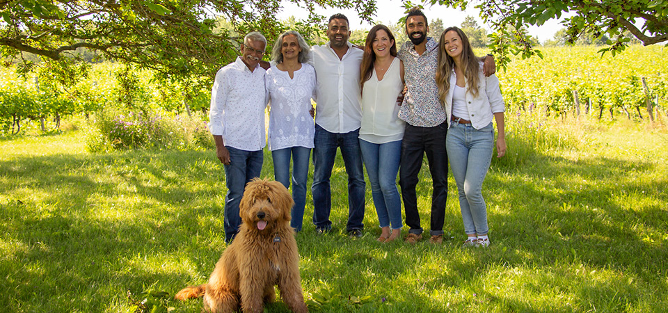 The Coutinho family stands together arm in arm on the lush green Avondale Sky property, with their dog sitting in from of them.. 