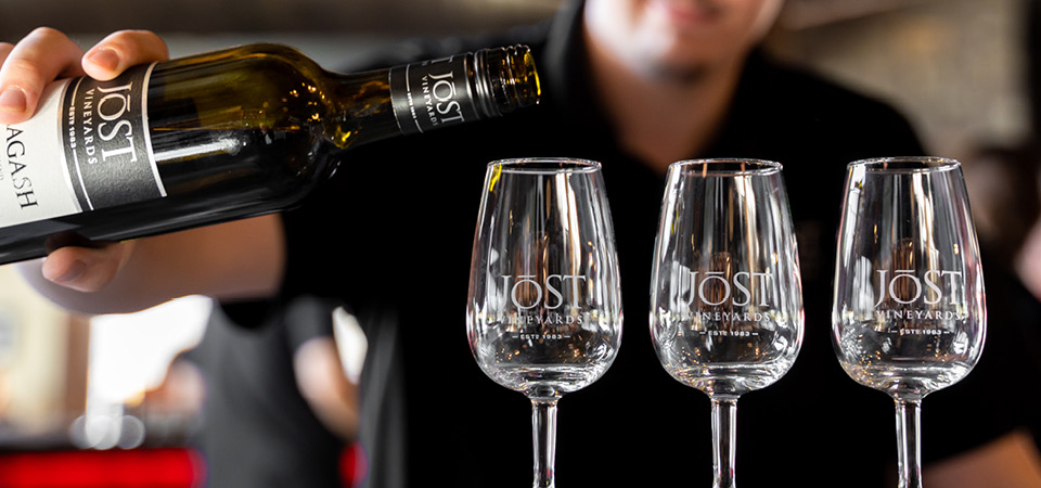 Bottle of Jost Vineyards wine being poured into three wine glasses