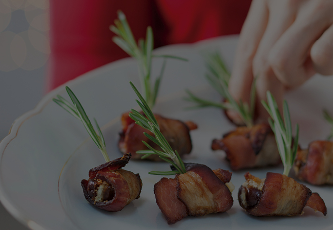Bacon wrapped dates with rosemary sprigs .