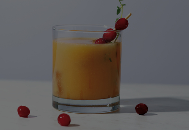 Orange coloured mocktail with cranberry and thyme.
