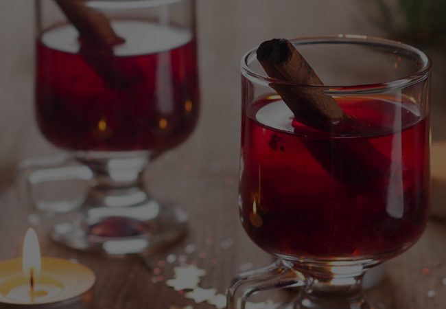Cranberry and Cinnamon Shrub Mocktail in clear mug with a cinnamon stick. 