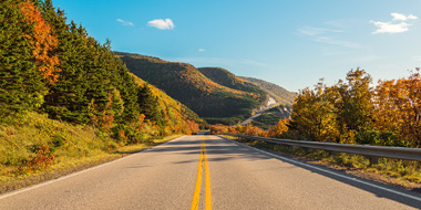 Empty road with mountain and trees with fall leaves. 