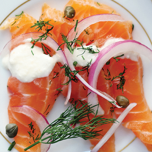 Plated salmon topped with onion slices and capers