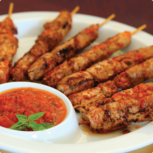 Moroccan Chicken Skewers on a plate with a small bowl of dipping sauce