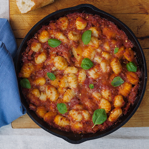 A loaded skillet filled with tomato sauce and gnocchi topped with chilli flakes