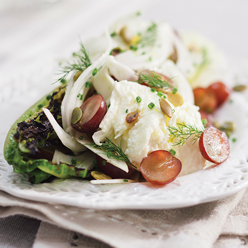A charred romaine salad topped with a chive garnish
