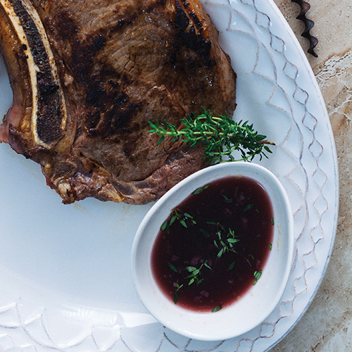 A rib eye steak plated with a red wine reduction sauce