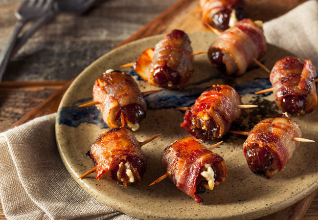 An assortment of bacon wrapped dates held together by toothpicks 