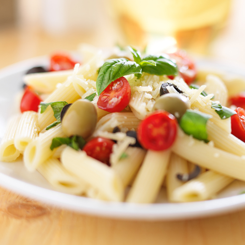 Mediterranean Penne with halved cherry tomatoes, green olives and basil